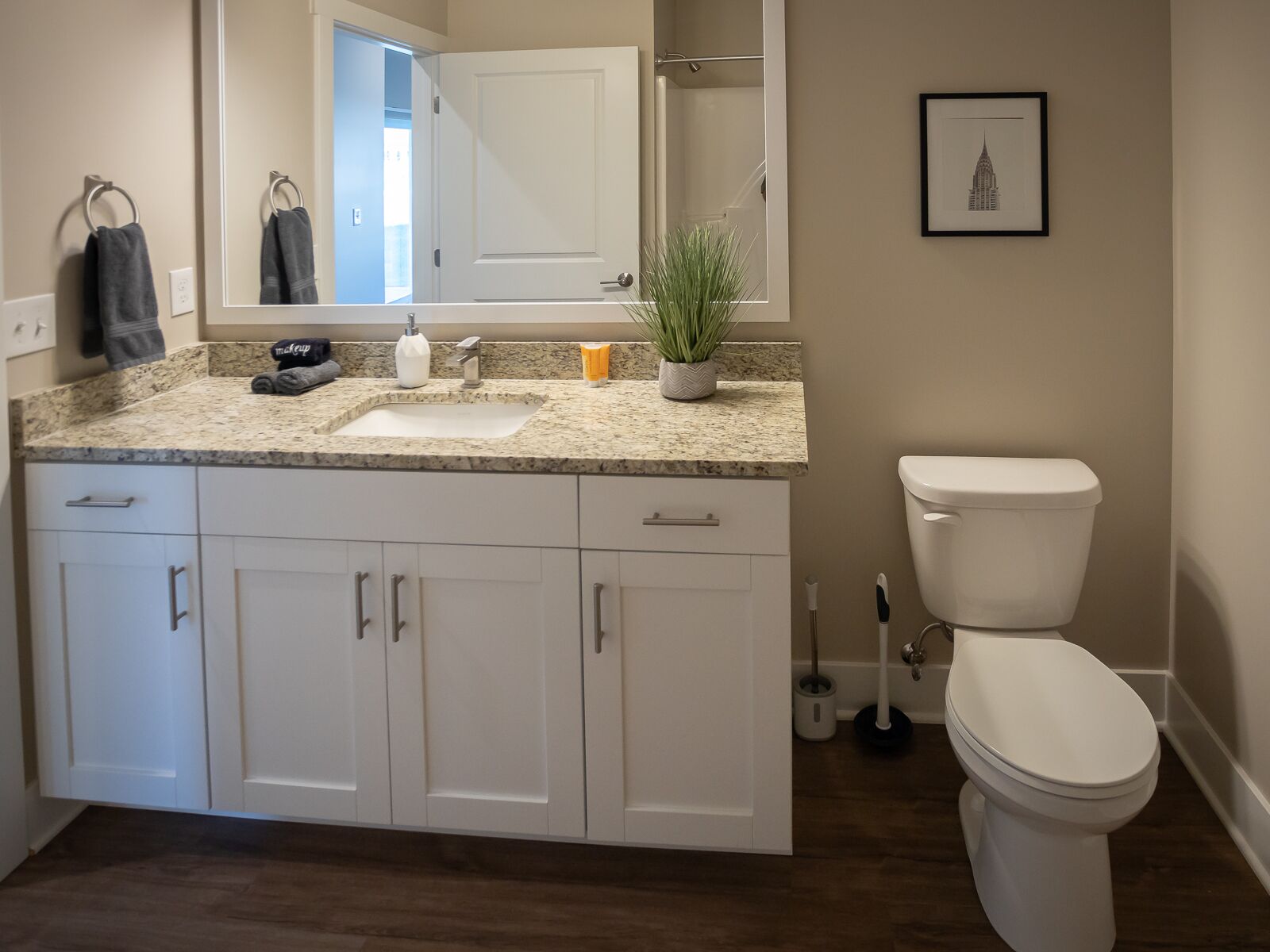 Un baño moderno con lavamanos, espejo, inodoro y armarios.