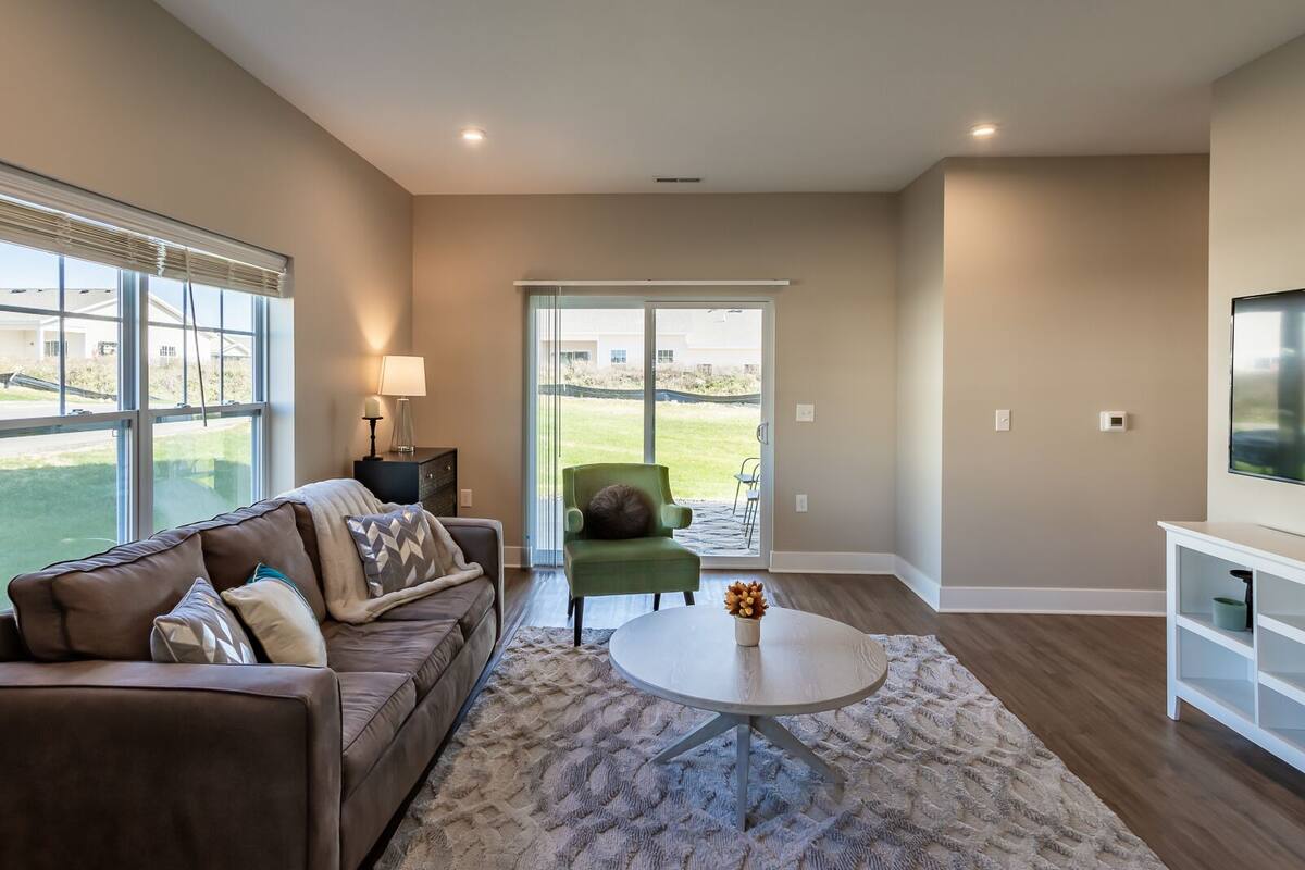 A modern living room with a brown leather sofa, a round coffee table, and a green armchair.