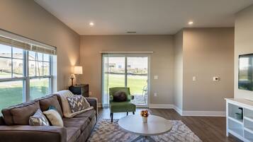 A modern living room with a brown leather sofa, a round coffee table, and a green armchair.