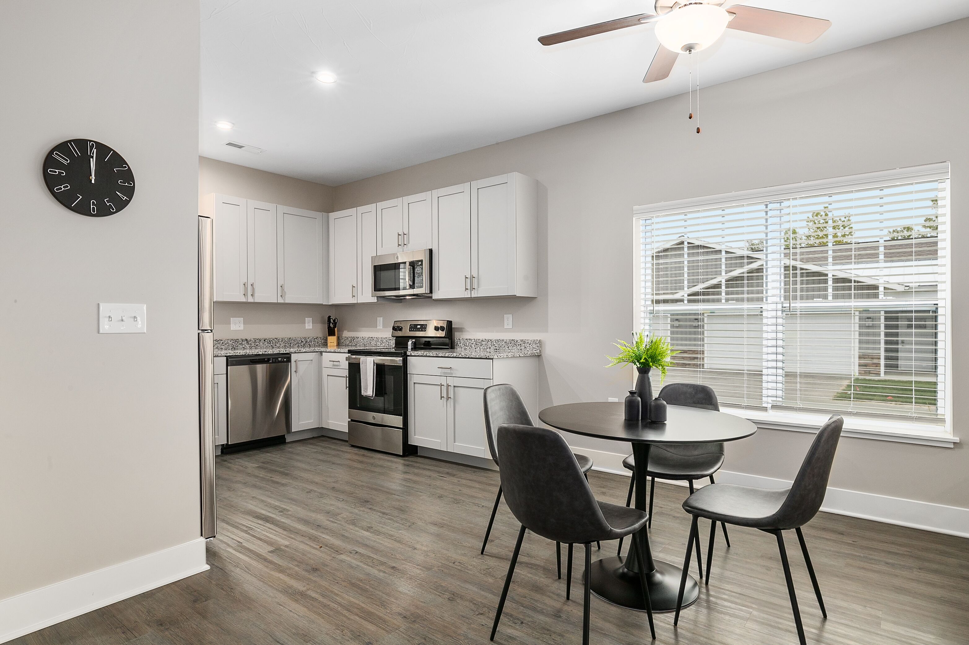 A modern kitchen with white cabinets, stainless steel appliances, and a dining area with a round table and chairs.