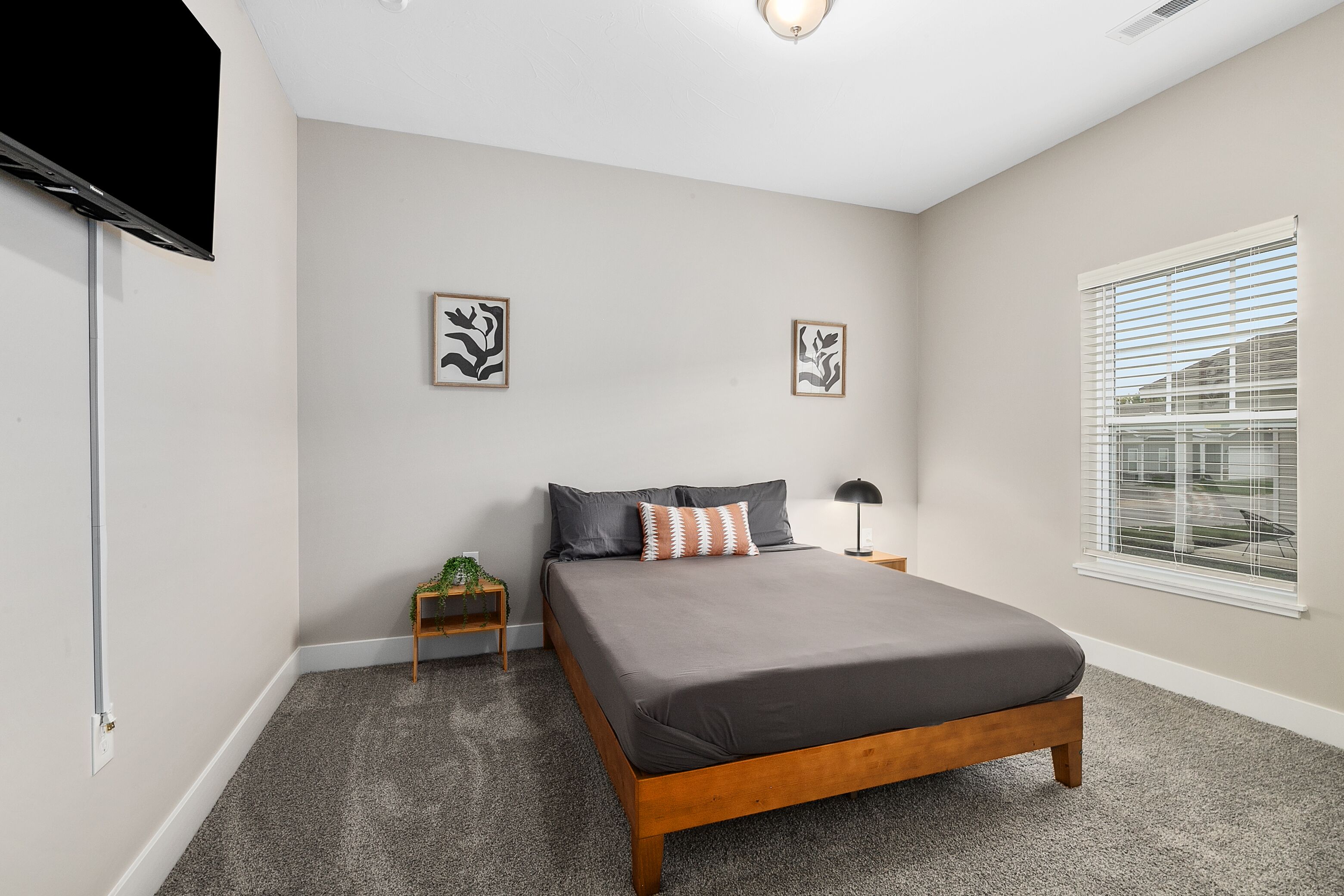 A bedroom with a bed, a nightstand, a lamp, and two framed pictures on the wall.