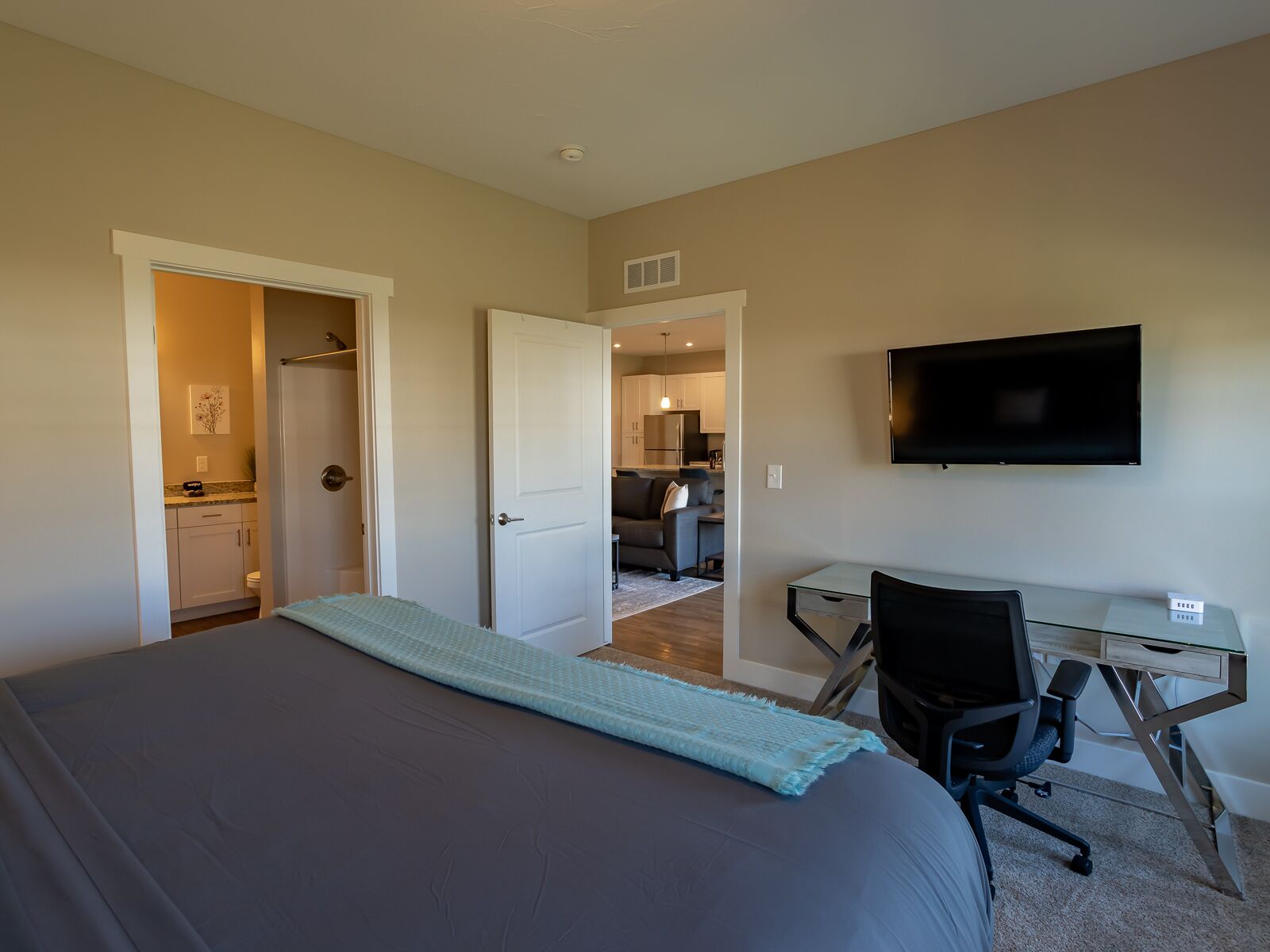 A bedroom with a bed, a desk, and a TV.