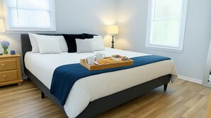 Une chambre à coucher avec un lit, des tables de chevet, un ventilateur de plafond et une fenêtre.