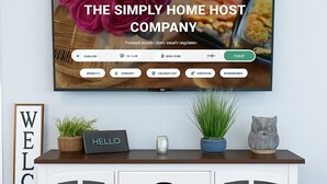 Un salon moderne avec un téléviseur affichant le site web d’une entreprise, un meuble blanc avec des tiroirs et des portes en verre, une pancarte « BIENVENUE » et des objets décoratifs, notamment une plante et une statuette de chat.
