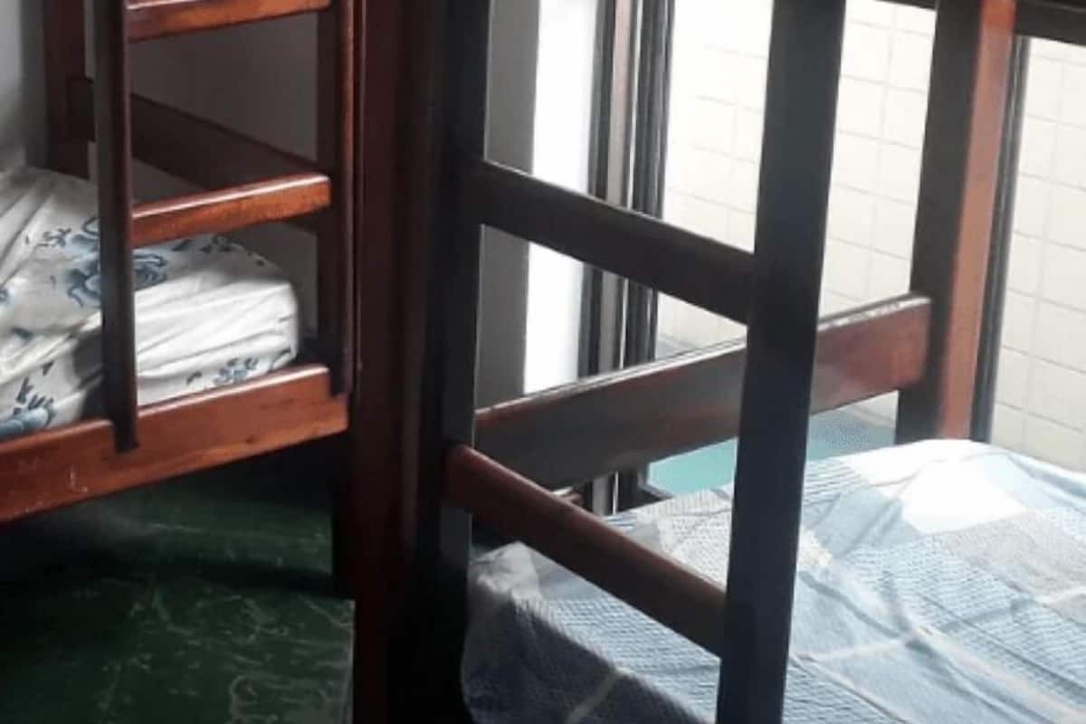 A wooden bunk bed with a patterned mattress and a window in the background.