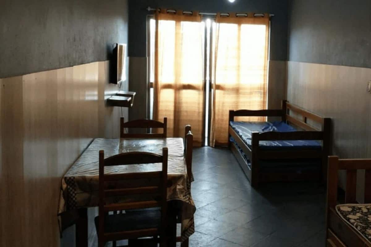 A room with two single beds, a wooden table, and chairs.