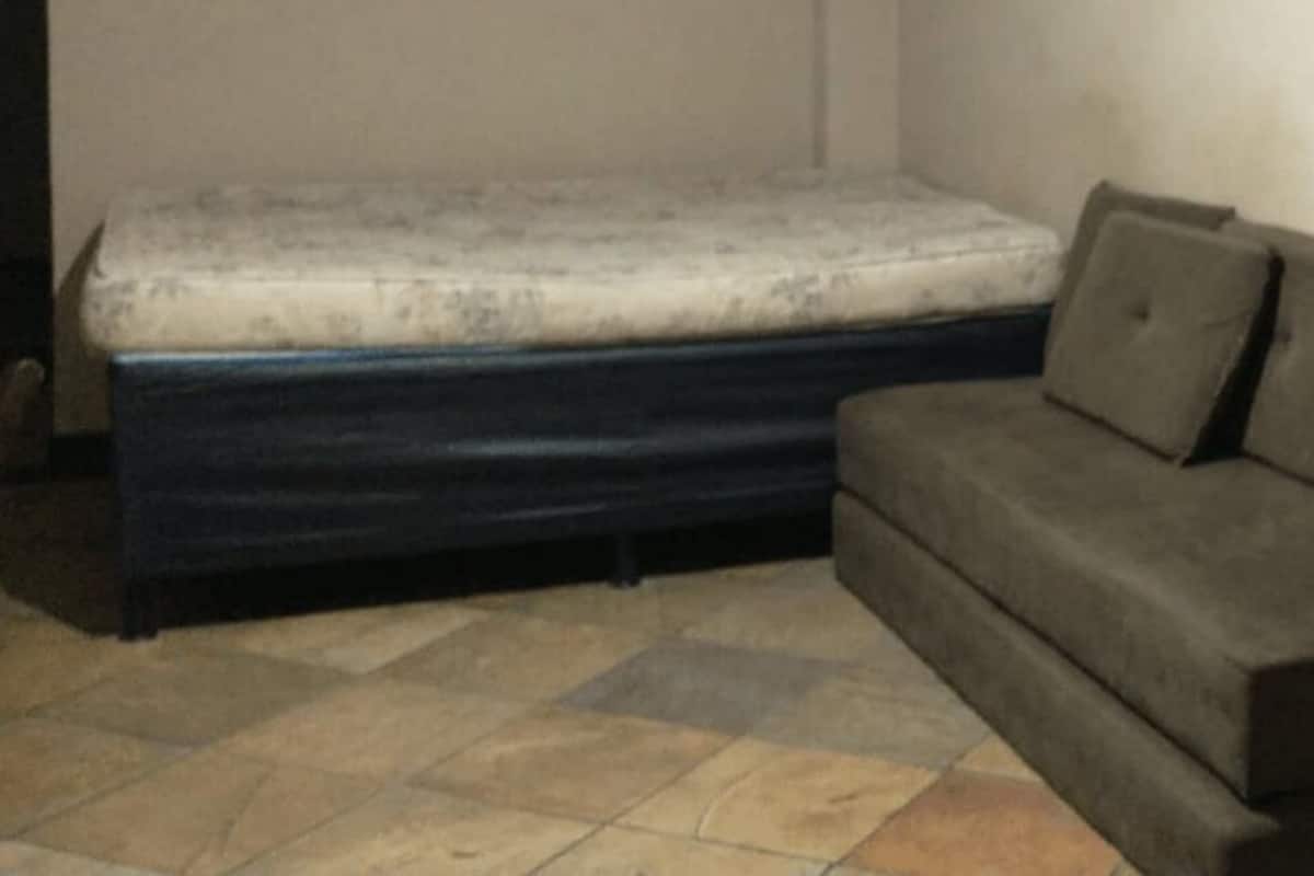 A room with a mattress and a sofa against a wall.