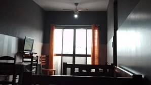 A room with a ceiling fan, a TV on a stand, a wooden chair, and a window with curtains. - Arraial do Cabo - Prainha (Arraial do Cabo)