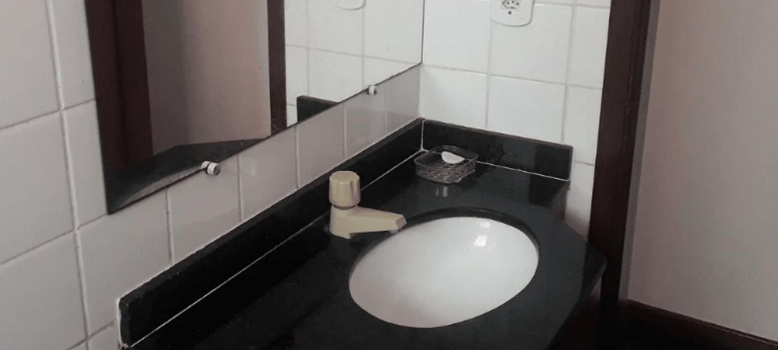 Une petite salle de bain moderne avec un lavabo noir, des carreaux blancs et un miroir.