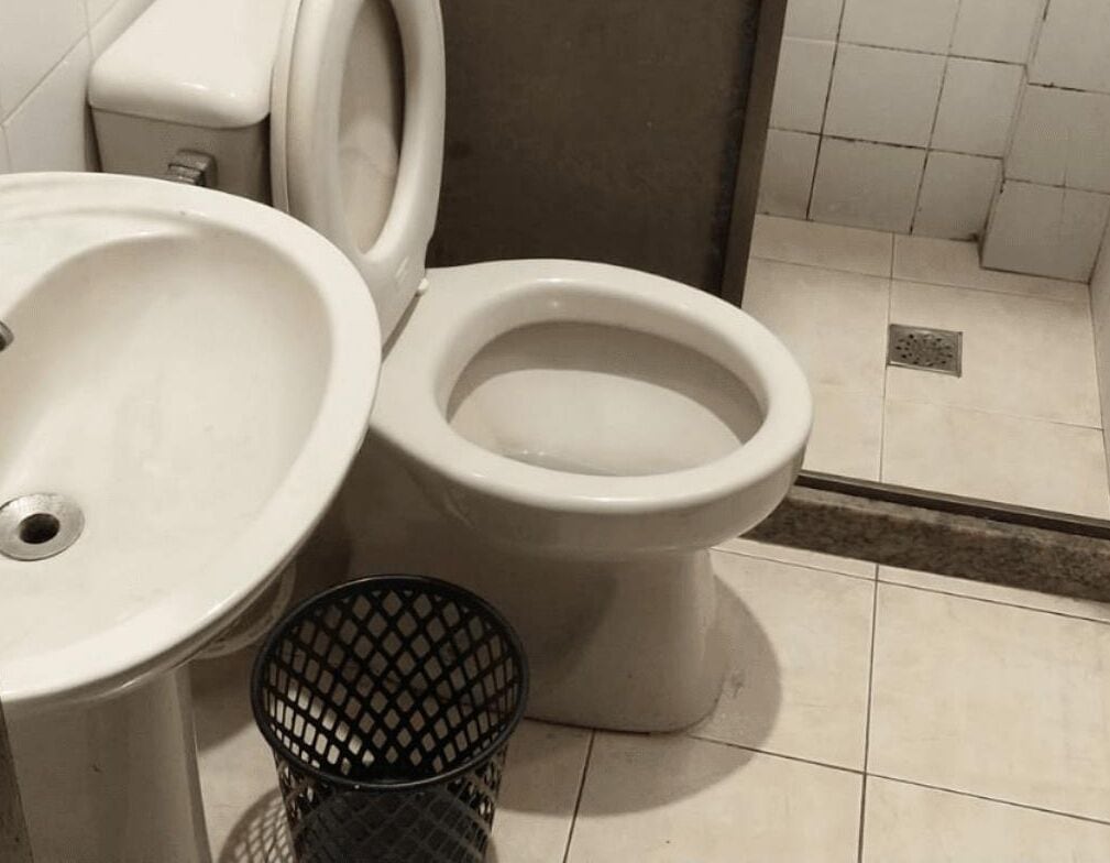 Un baño con lavamanos, inodoro y un cubo de basura.