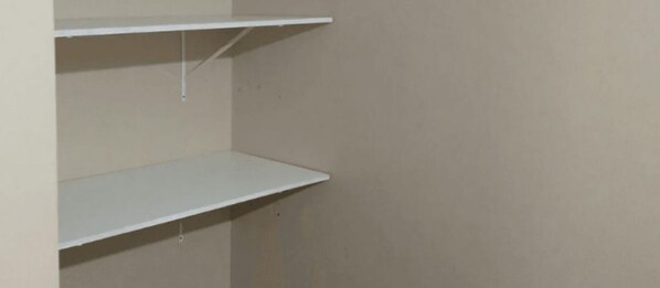 Un rincón de una habitación con dos estantes blancos contra una pared lisa.