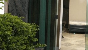 A hotel room with a glass door, a bed, and a small potted plant. - Arraial do Cabo - Prainha (Arraial do Cabo)