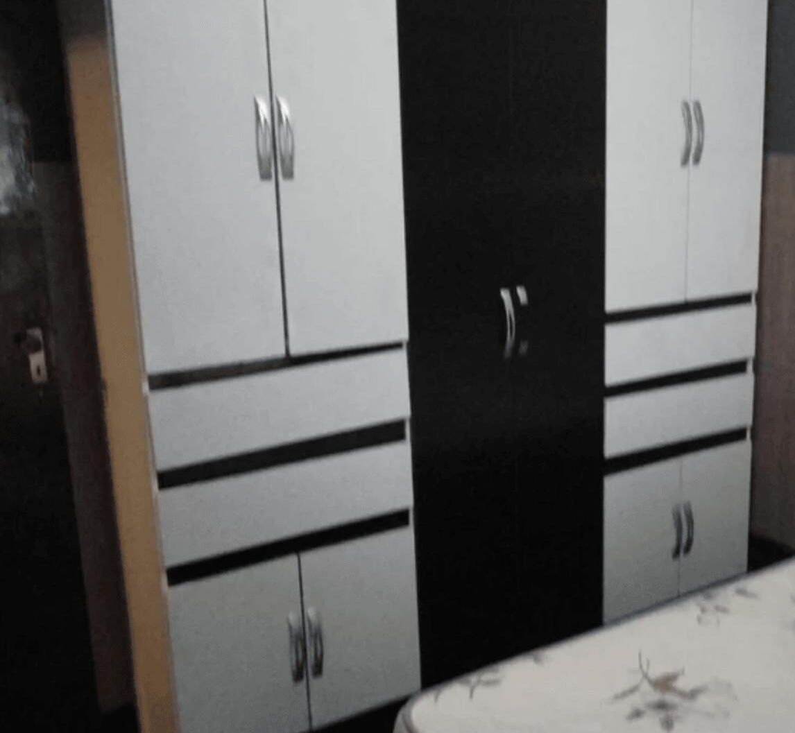 Une chambre avec un lit, une armoire à deux portes et un miroir.
