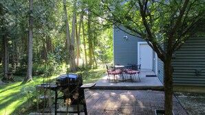 Ein Garten mit Grill, Tisch und Stühlen sowie einem Baum.