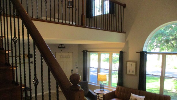 Ein großzügiger Wohnbereich mit Treppe, Sofa, Couchtisch und Blick ins Freie.
