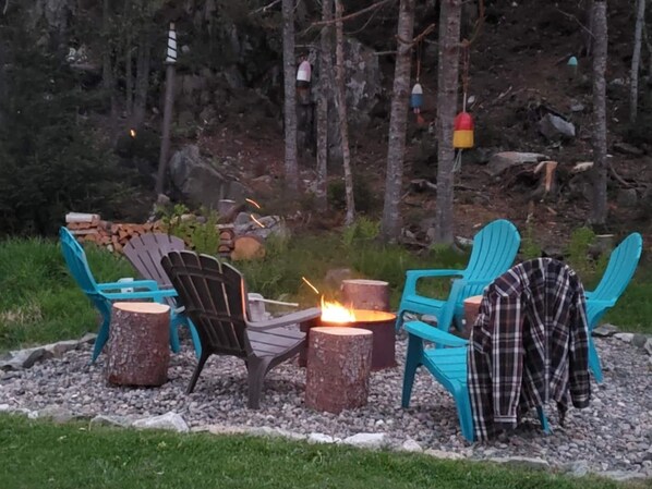 A cozy outdoor seating area with Adirondack chairs and a fire pit.