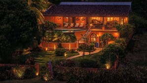 Uma casa com piscina, cercada por vegetação exuberante e palmeiras.