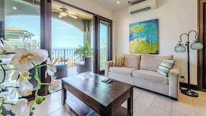A modern living room with a sofa, coffee table, and a painting on the wall. - 360 Splendor 403-Condo with Breakfast Included (360 Splendor)