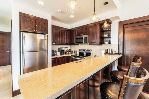 A modern kitchen with dark wood cabinets, stainless steel appliances, and a granite countertop. - 360 Splendor 403-Condo with Breakfast Included (360 Splendor)