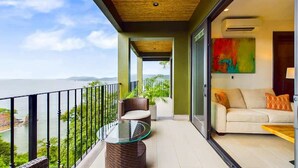 A balcony with a glass table and wicker chairs, overlooking a coastal view. - 360 Splendor 405-Condo with Breakfast Included (360 Splendor)