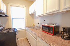 A kitchen with white cabinets, a stove, a microwave, and a coffee maker. - Lovely 3 bedroom apartment V (Providence)