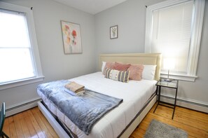 A bedroom with a bed, a bedside table, a window, and a wall with two framed pictures. - Lovely 3 bedroom apartment V (Providence)