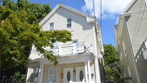 A two-story house with a front porch, a small staircase, and a garage door.