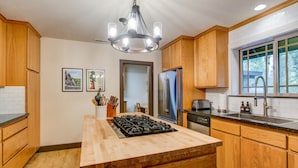 Una cocina con armarios de madera, una isla central con estufa, un refrigerador y un ventanal con vistas.