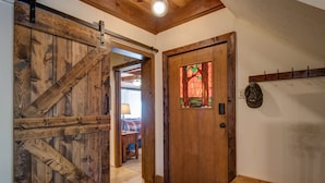 Una puerta de madera con un panel de vidrio, un perchero y un banco.