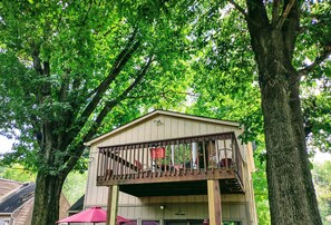 A wooden deck with a railing, surrounded by trees.