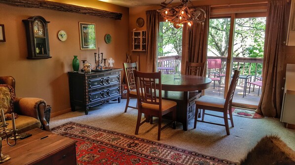 A cozy dining area with a wooden table and chairs, a vintage clock, and a chandelier.