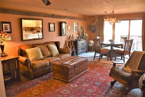 A cozy living room with a leather sofa, a wooden coffee table, and a dining area with a chandelier.