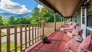 A covered porch with outdoor seating, a wooden railing, and a view of mountains and trees. - July 4 special: Sleep 20, 6BR/6BA. Pool, tennis, views, resort. Dogs loved! (Manchester)