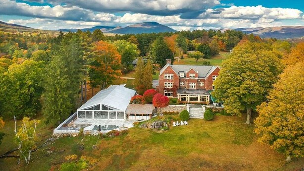 A large, traditional house with a prominent front entrance, surrounded by a lush landscape with autumn-colored trees and a clear blue sky. - July 4 special: Sleep 20, 6BR/6BA. Pool, tennis, views, resort. Dogs loved! (Manchester)