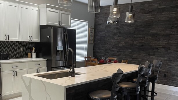 Una cocina moderna con una isla grande, taburetes de bar e iluminación colgante.