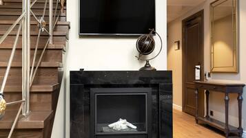A modern interior with a fireplace, a mounted television, and a staircase.