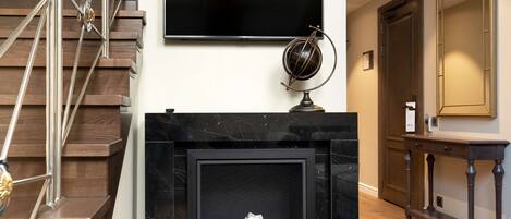 A modern interior with a fireplace, a mounted television, and a staircase.
