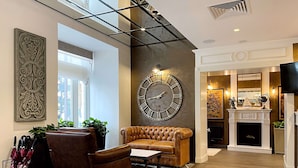 A spacious lobby with a large wall clock, leather furniture, and a fireplace. - Best Western Plus Market Square Lviv (Lviv)