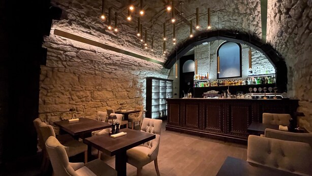 A cozy bar area with stone walls, wooden furniture, and a bar stocked with bottles. - Best Western Plus Market Square Lviv (Lviv)