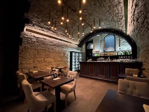 A cozy bar area with stone walls, wooden furniture, and a bar stocked with bottles. - Best Western Plus Market Square Lviv (Lviv)