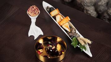 A dessert plate with a golden bowl, a white dessert spoon, and a white serving dish with bread and berries.