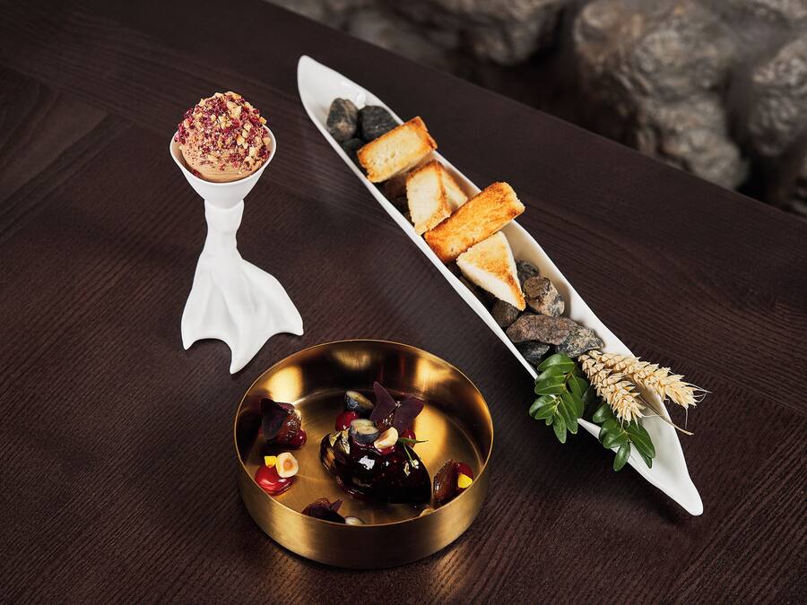 A dessert plate with a golden bowl, a white dessert spoon, and a white serving dish with bread and berries.