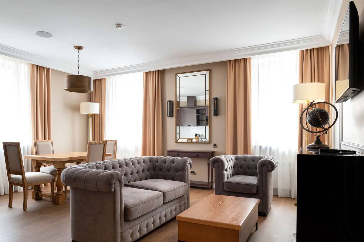 A modern living room with a sofa, armchair, coffee table, and dining area.