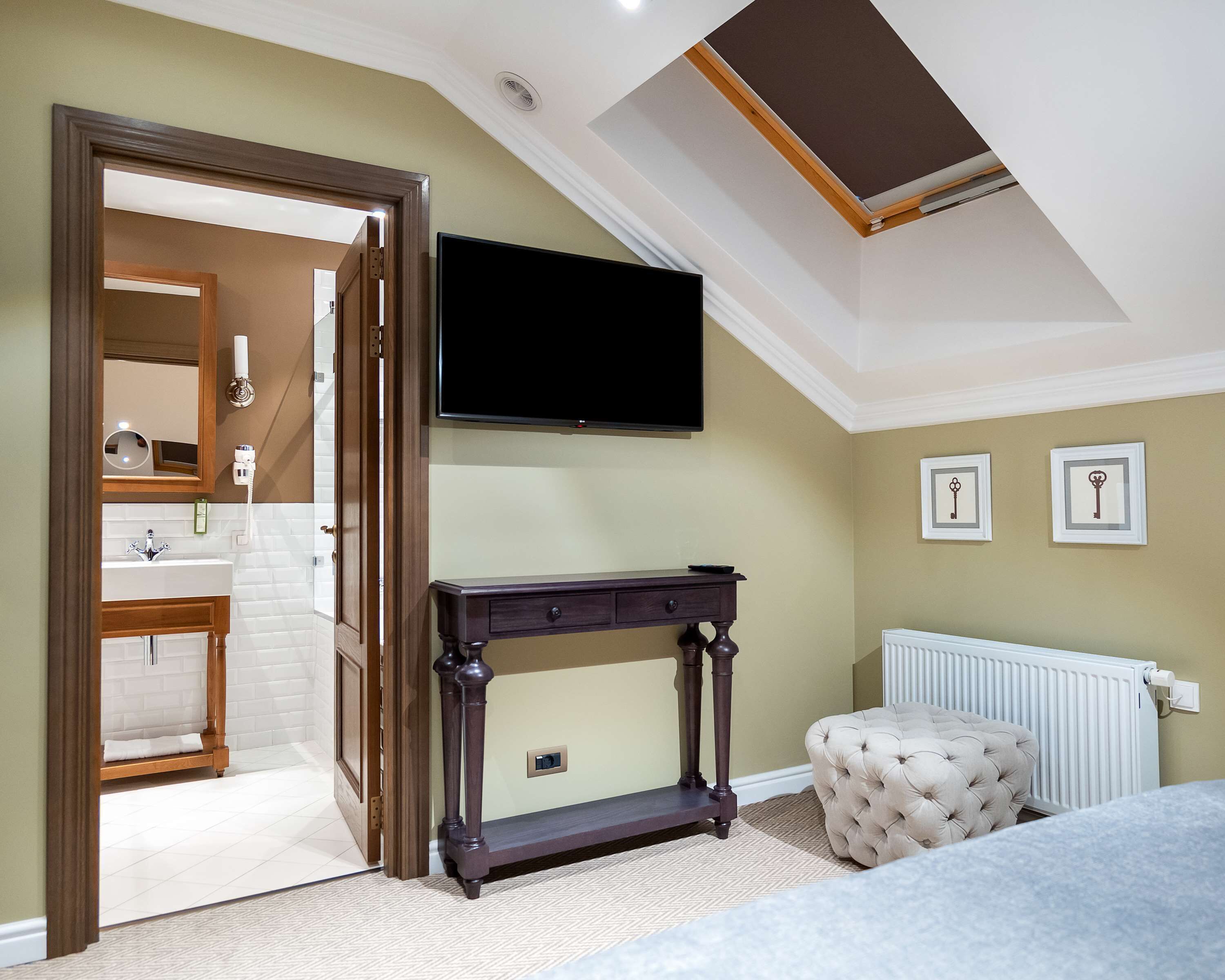 Une chambre à coucher avec un grand lit, une table de chevet, un téléviseur fixé au mur et un radiateur.