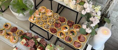 A buffet table with various food items including appetizers, salads, and sandwiches.