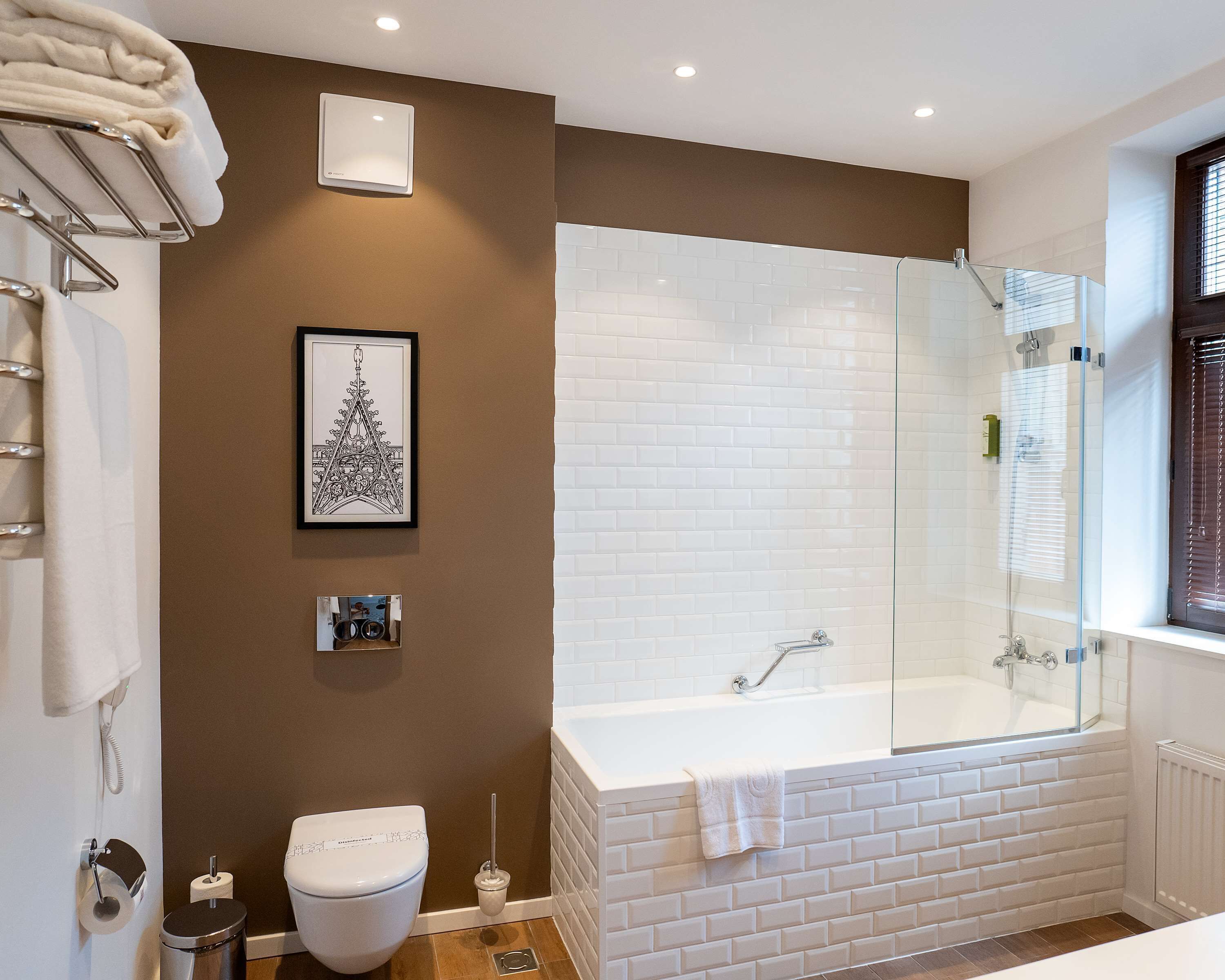 A modern bathroom with a white bathtub, a glass-enclosed shower, and a toilet.