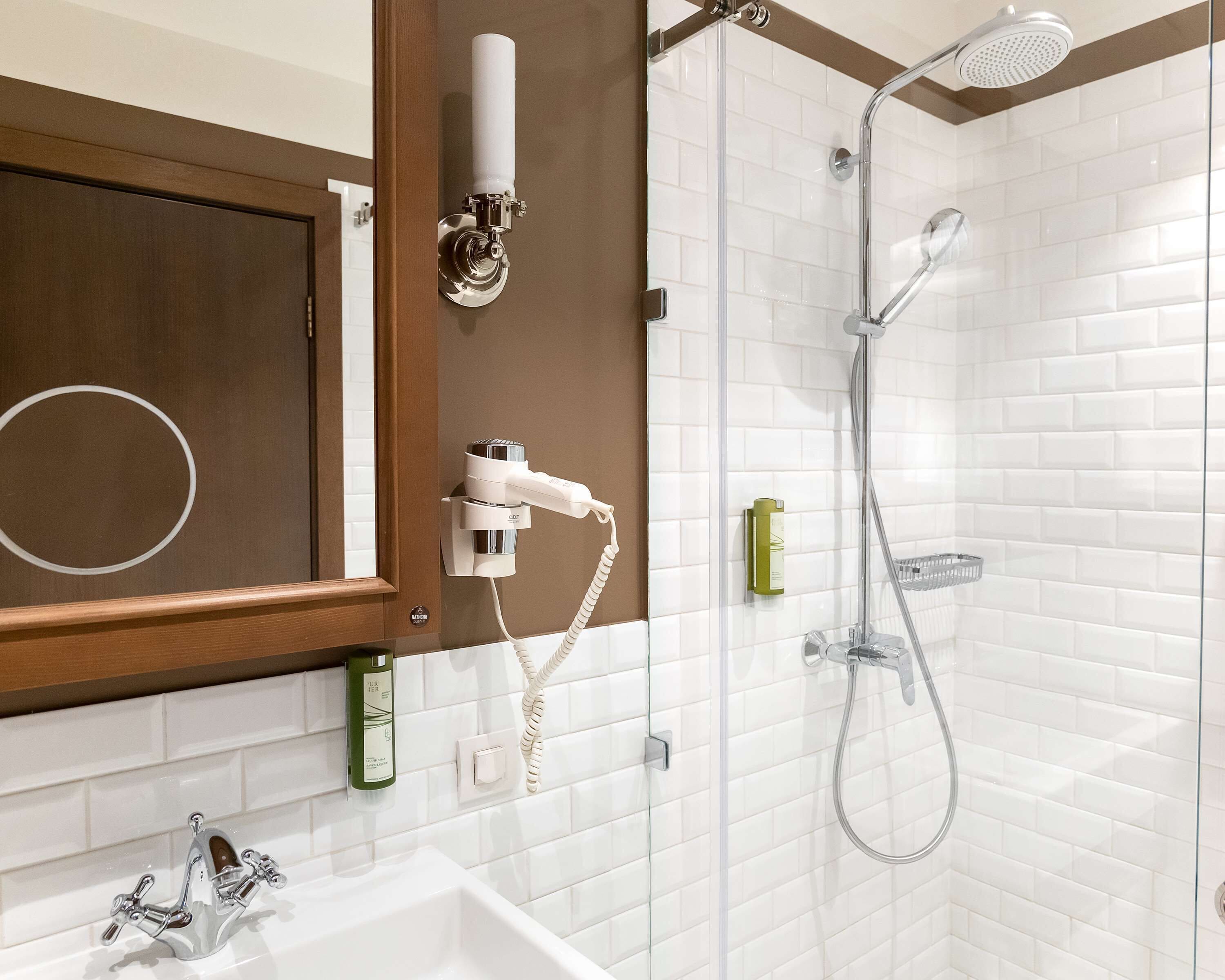 A bathroom with a white bathtub, a shower with a handheld showerhead, and a towel rack.