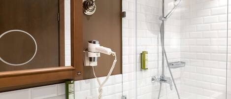 A bathroom with a white bathtub, a shower with a handheld showerhead, and a towel rack.