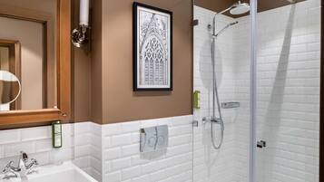 A bathroom with a sink, mirror, framed artwork, and a glass-enclosed shower area.