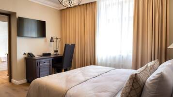 Une chambre d’hôtel avec un lit, un bureau et une chaise, une télévision et un lustre.